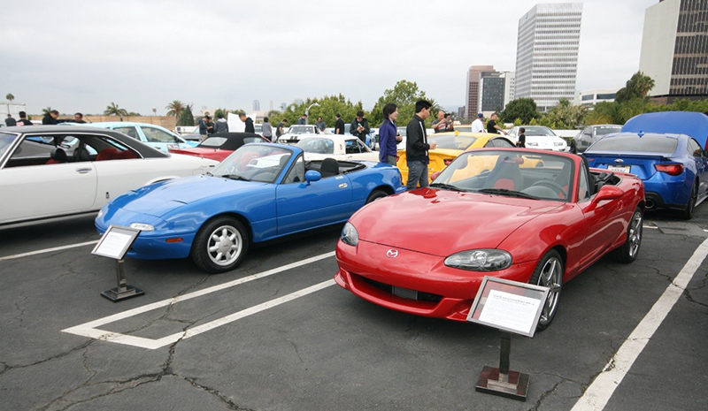 Blue (left) and red (right) Mazda MX-5 roadsters parked at the Petersen Automotive Museum's Japanese Car Cruise in