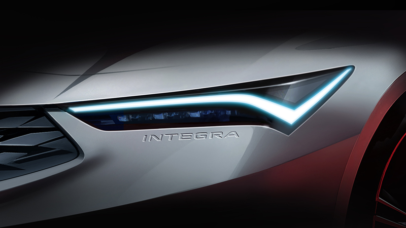 A Teaser Image of the 2022 Acura Integra showing just the headlight with the "Integra" logo embossed in the bumper just below.