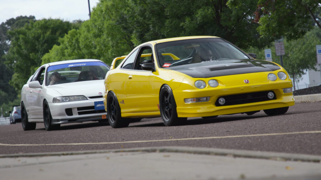 Yellow DC2 Acura Integra Type R followed by a white Acura Integra Type R with JDM front end as seen at the 2021 Tuner Evolution show in Philadelphia