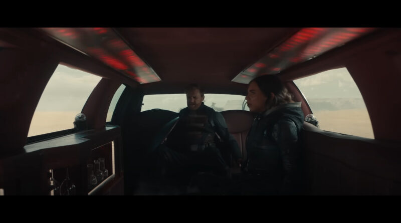 The interior of a dark red 1990s Lincoln Town Car limo as seen in the Marvel Studios Film Thunderbolts*. The character John Walker can be seen sitting in the back seat with the character "Ghost" sitting on the right side of the frame. Above them both is red mood lighting panels mounted in the ceiling of the limo.